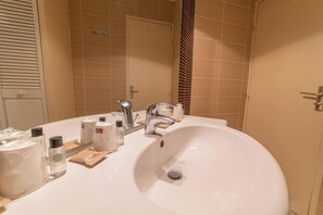 A bathroom with a large white sink, a mirror, and beige tiles. - VVF Serre Chevalier Briançon (Monetier-les-Bains)