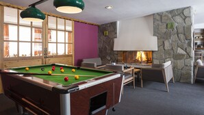 Una mesa de billar con bolas, una chimenea y zonas de estar.