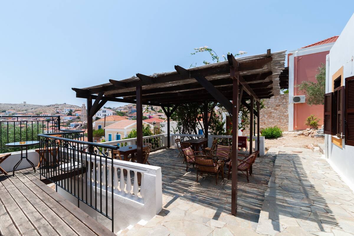 Um terraço no telhado com móveis de exterior, uma pérgula e vista para a paisagem urbana.