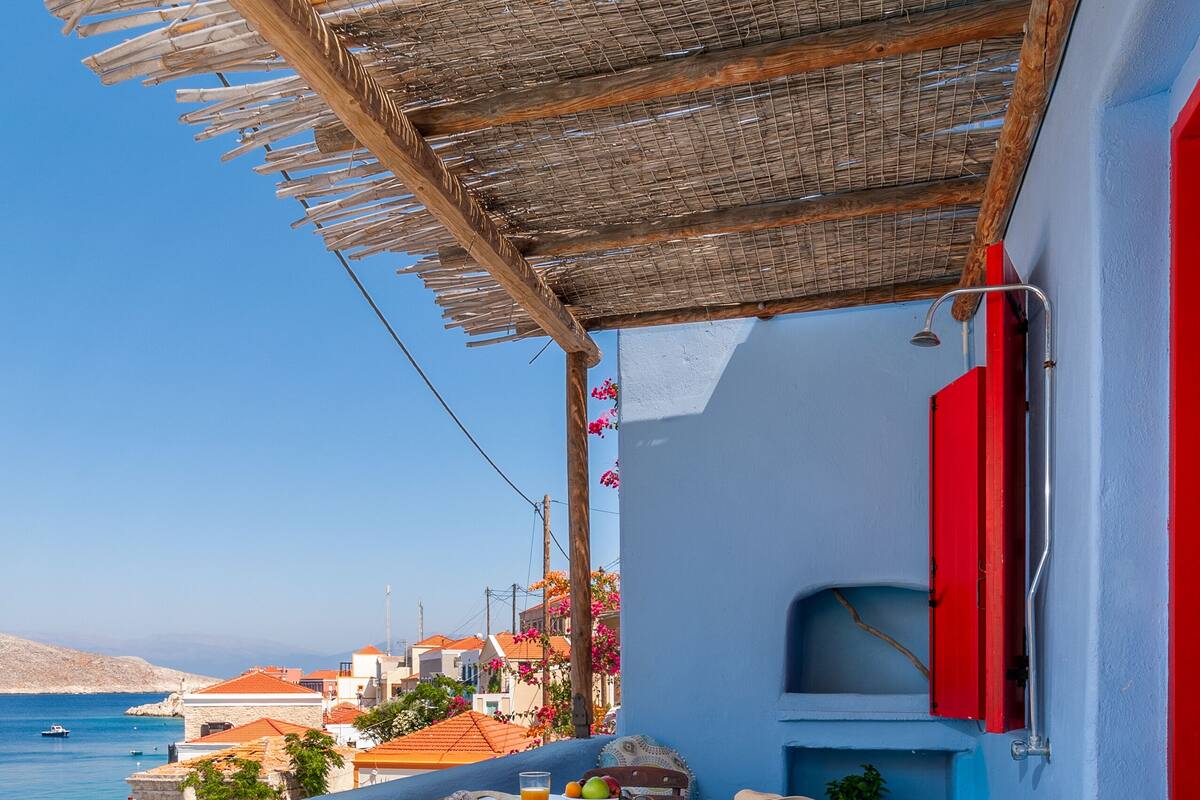 Uma varanda com mesa, cadeiras e vista para o mar.