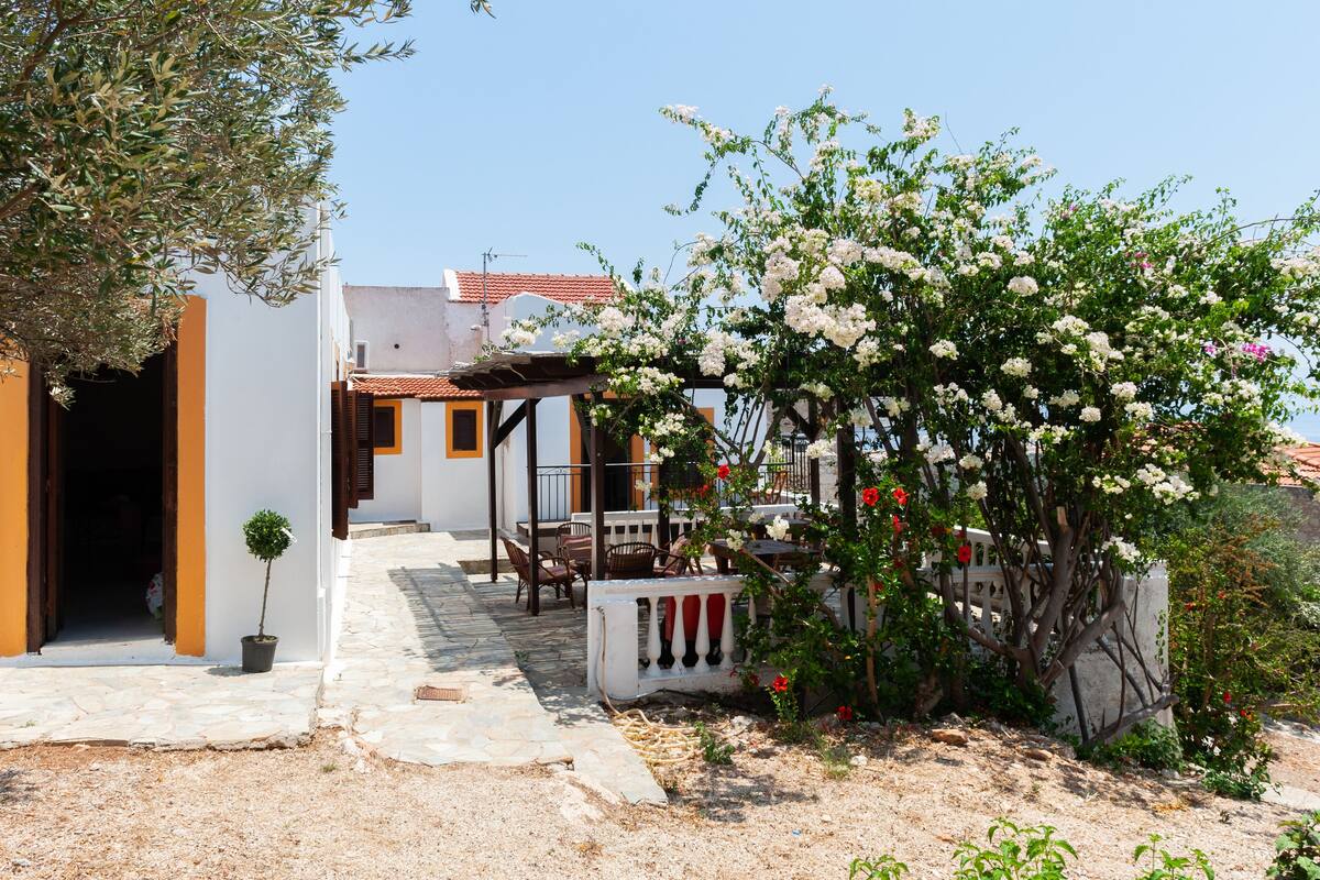 Um edifício em estilo mediterrâneo tradicional, com um caminho de pedra que leva a uma área de estar coberta ao ar livre.