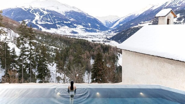 Eine Person in einem Swimmingpool vor einer Berglandschaft.