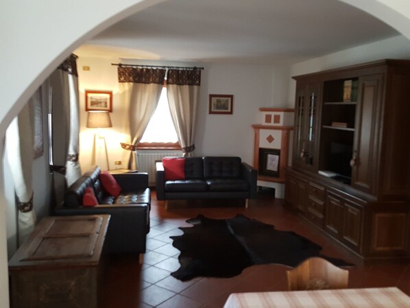 Una sala de estar con un sofá, televisor, mueble y alfombra.