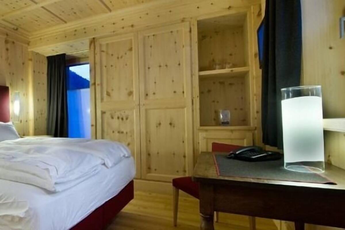 Een kamer met houten lambrisering, een bed, een bureau en een stoel.