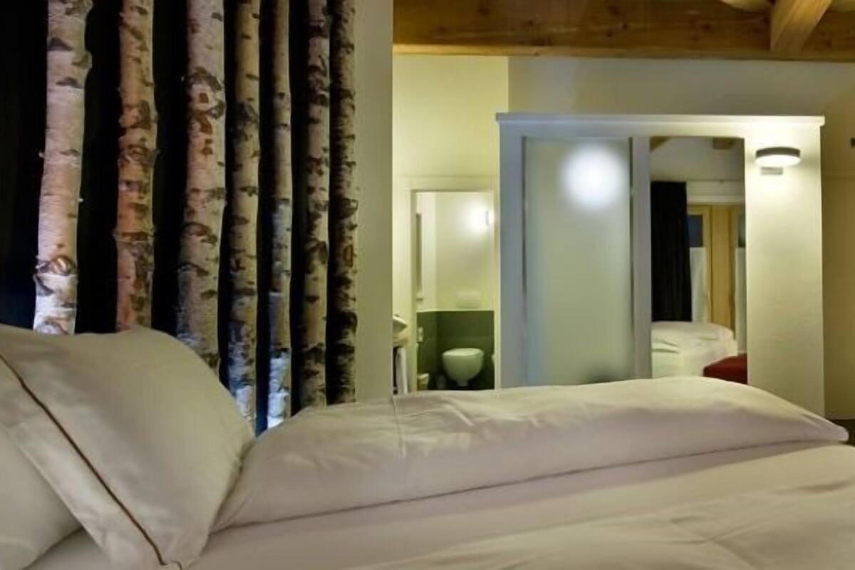 Een hotelkamer met een bed, een televisie en een badkamer die door een geopende deur zichtbaar is.
