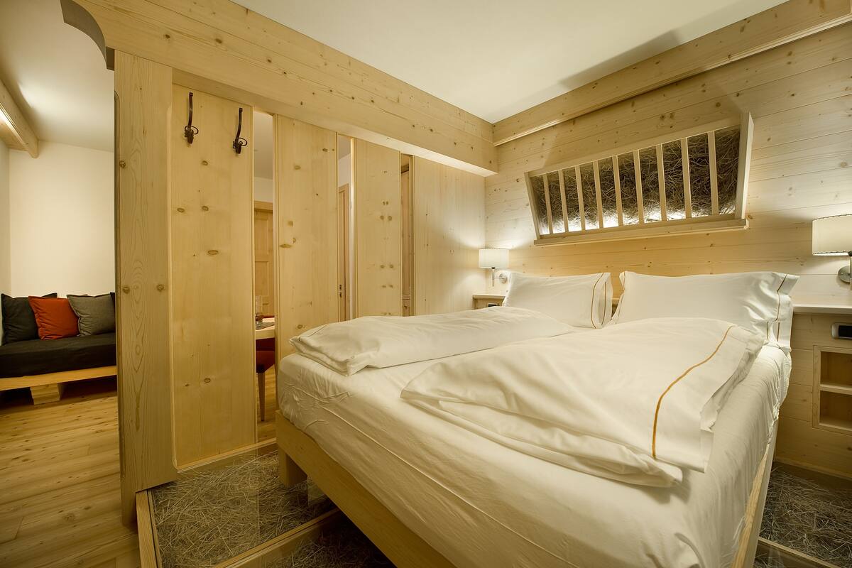 Een houten slaapkamer met een groot bed, een houten kledingkast en een raam met uitzicht op een boom.