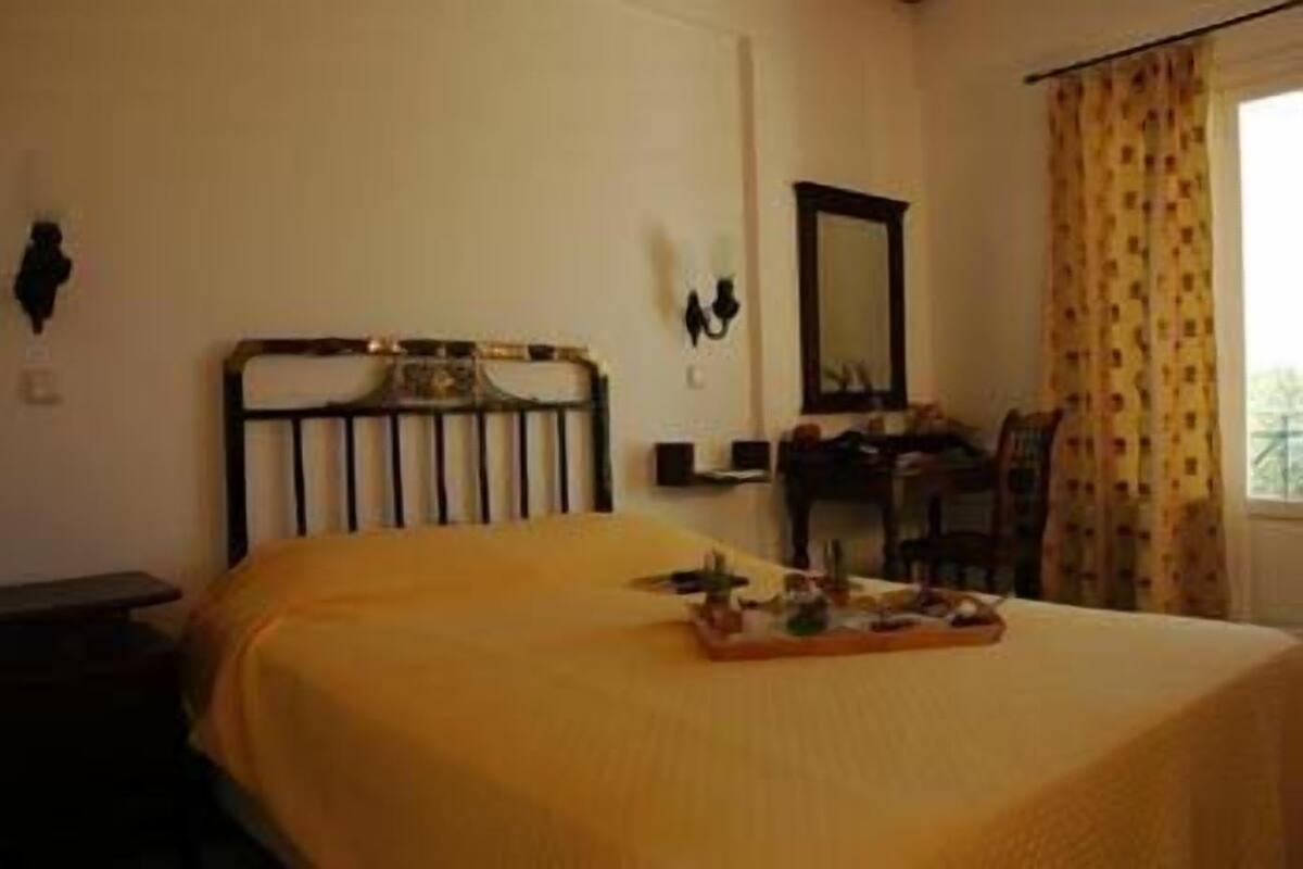 A room with a bed, a desk, a chair, and a window with curtains.