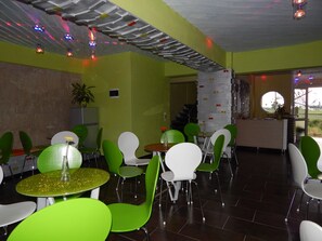 Een restaurant met groene en witte stoelen, een groene tafel en een modern plafondontwerp.