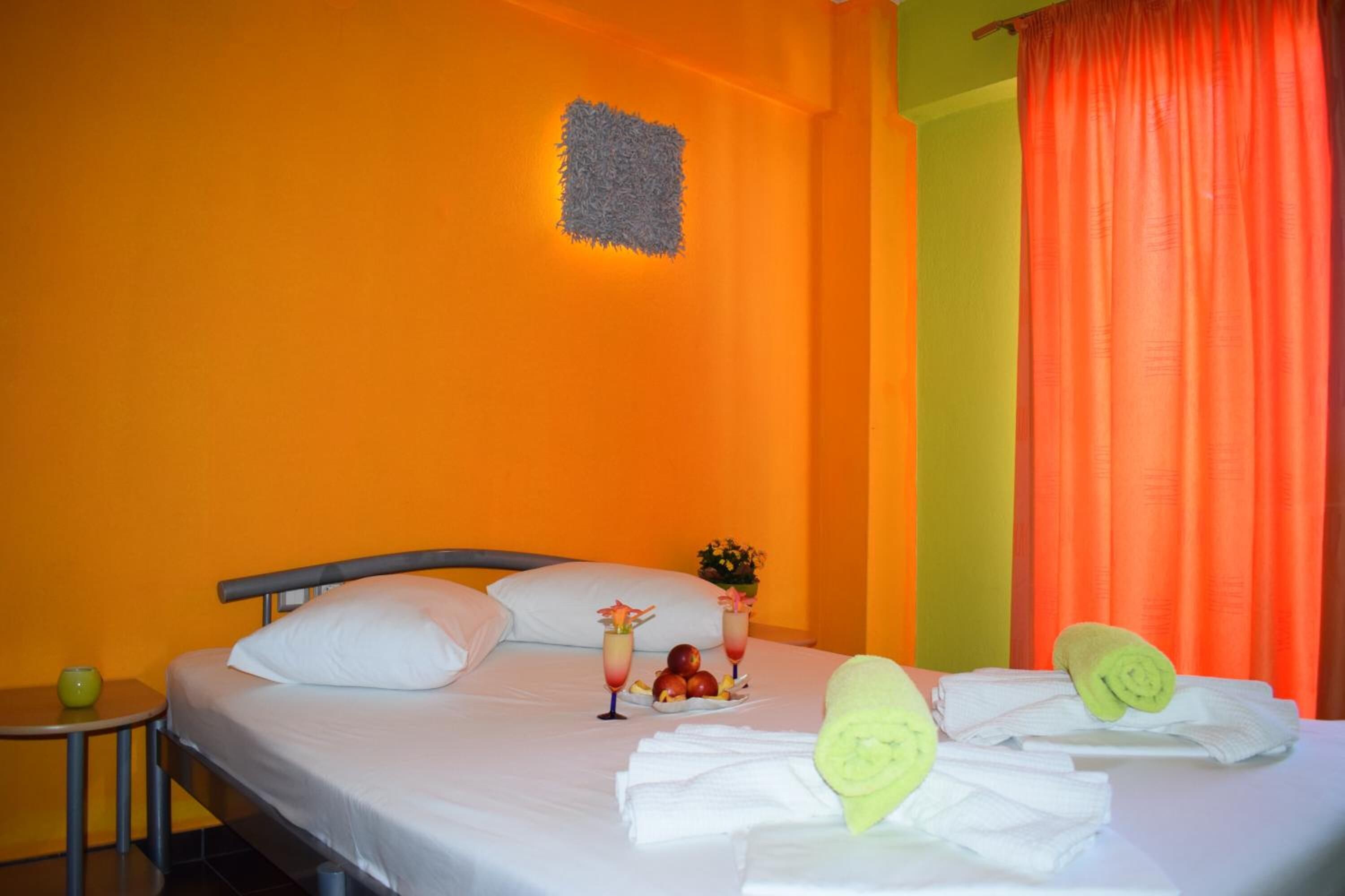 A hotel room with a bed, a small table with a vase, and a wall-mounted light fixture.