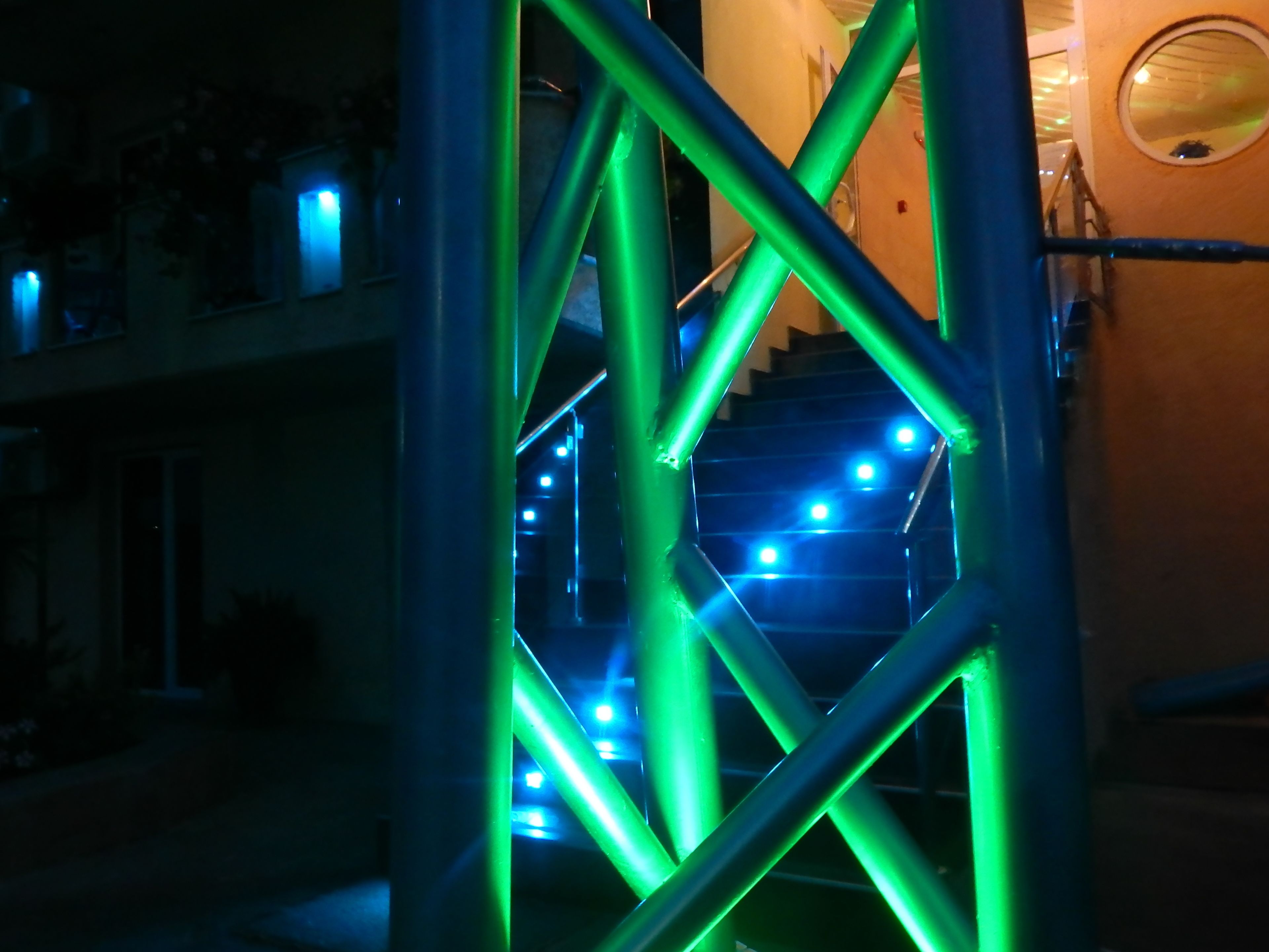 Un escalier avec des poutres de soutien vertes et un éclairage bleu.