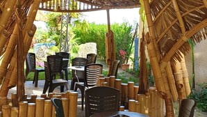 Une structure extérieure en bambou, avec des tables et des chaises.