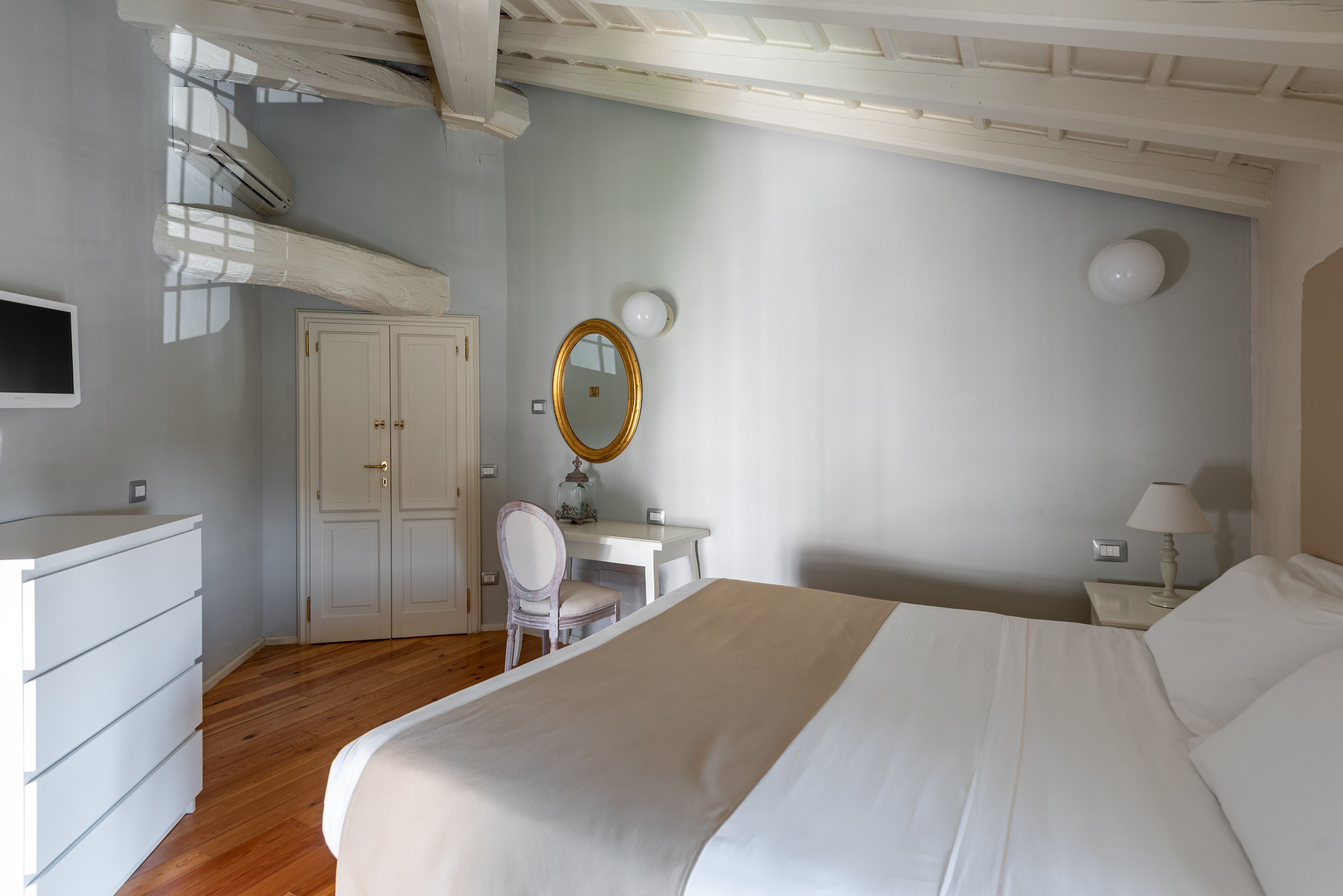 Un dormitorio con cama, escritorio, silla, armario y espejo.