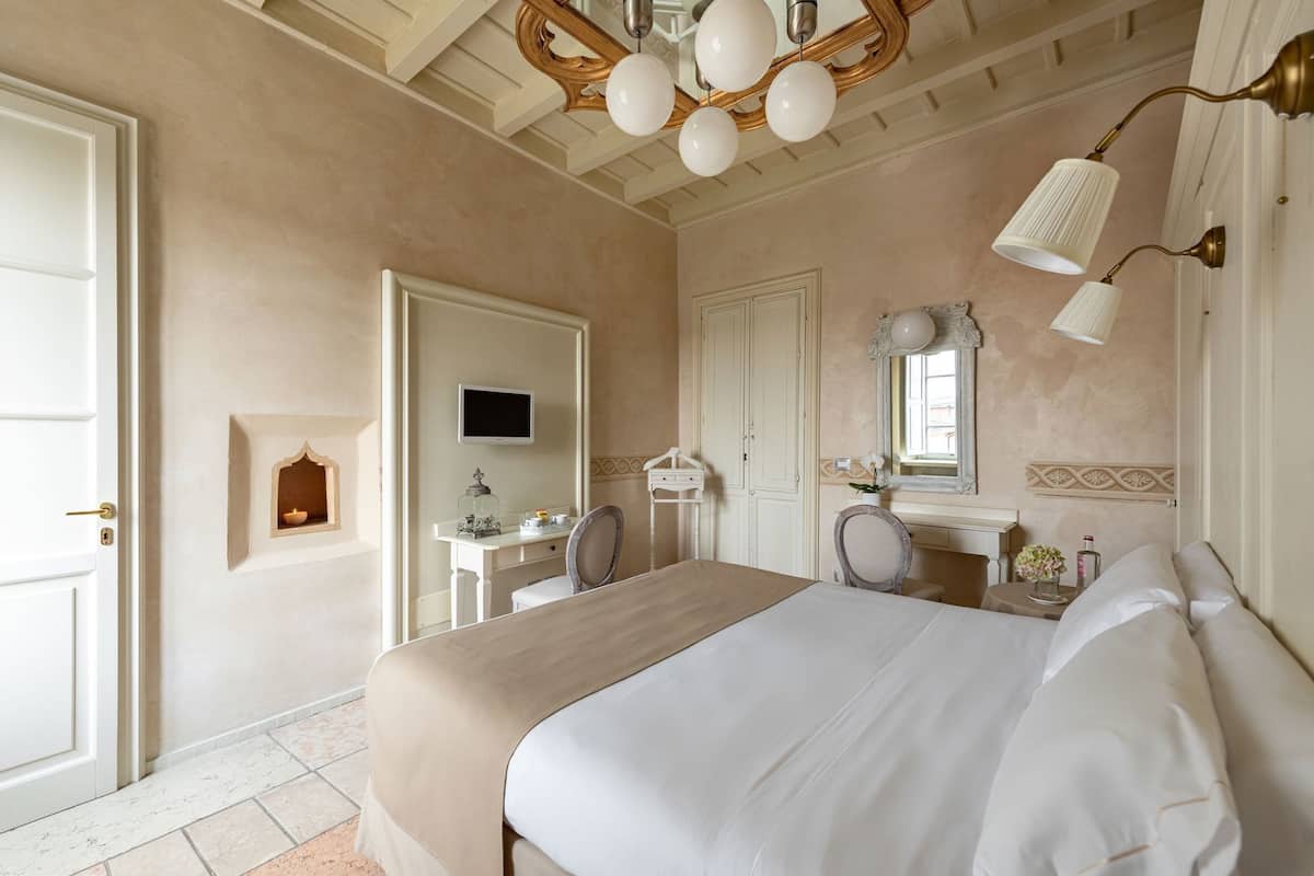 A hotel room with a bed, a desk, a chair, a television, and a bathroom.