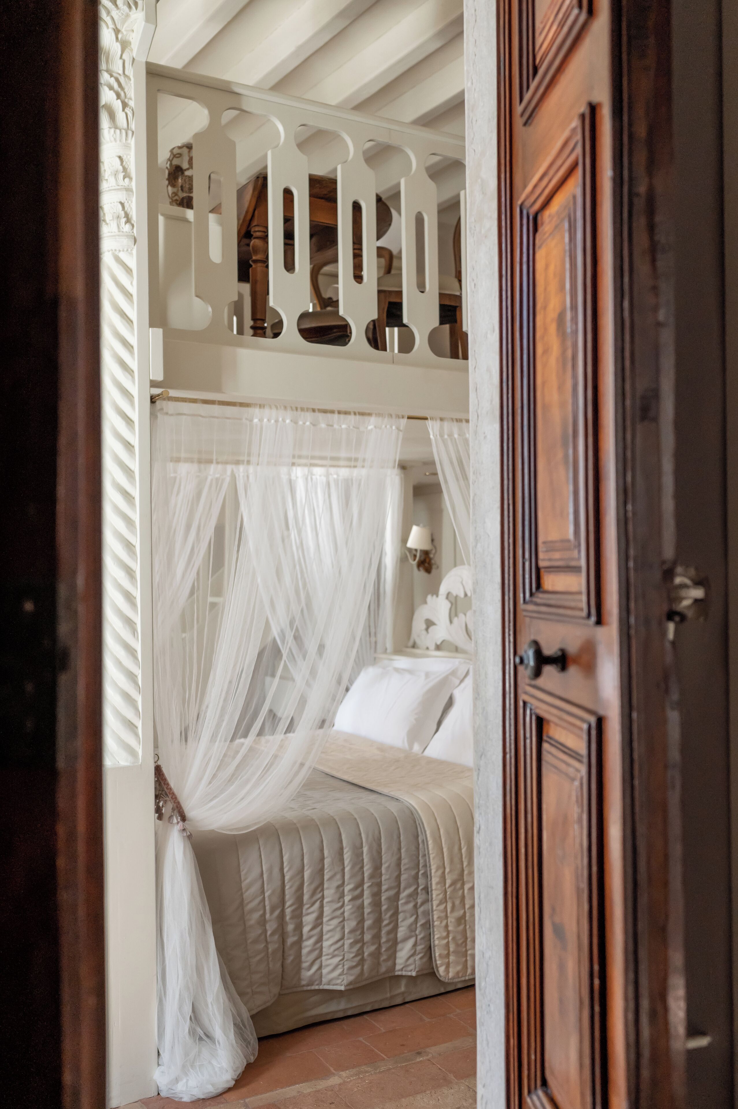 A bedroom with a four-poster bed, a canopy, and a wooden door.