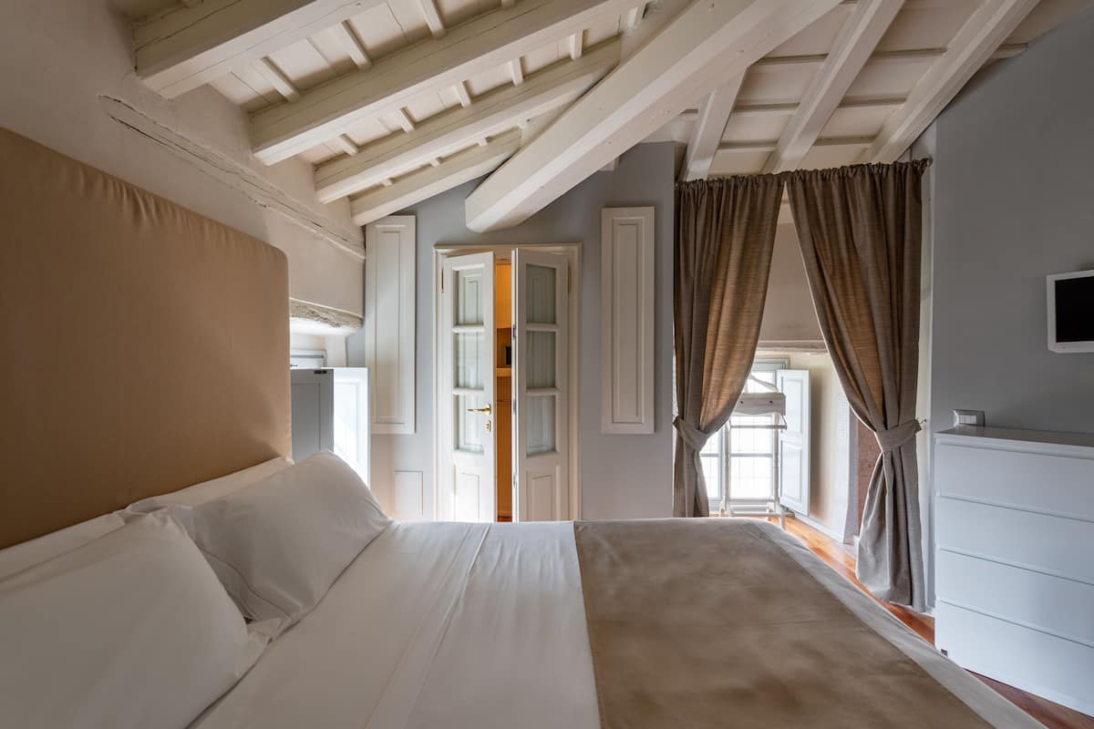 A bedroom with a large bed, a wardrobe, and a window with curtains.