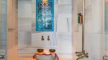 Ein modernes Badezimmer mit Dusche, einem blauen Wanddekor, einem Waschbecken mit zwei Becken und einem Paar Schuhe auf dem Boden.