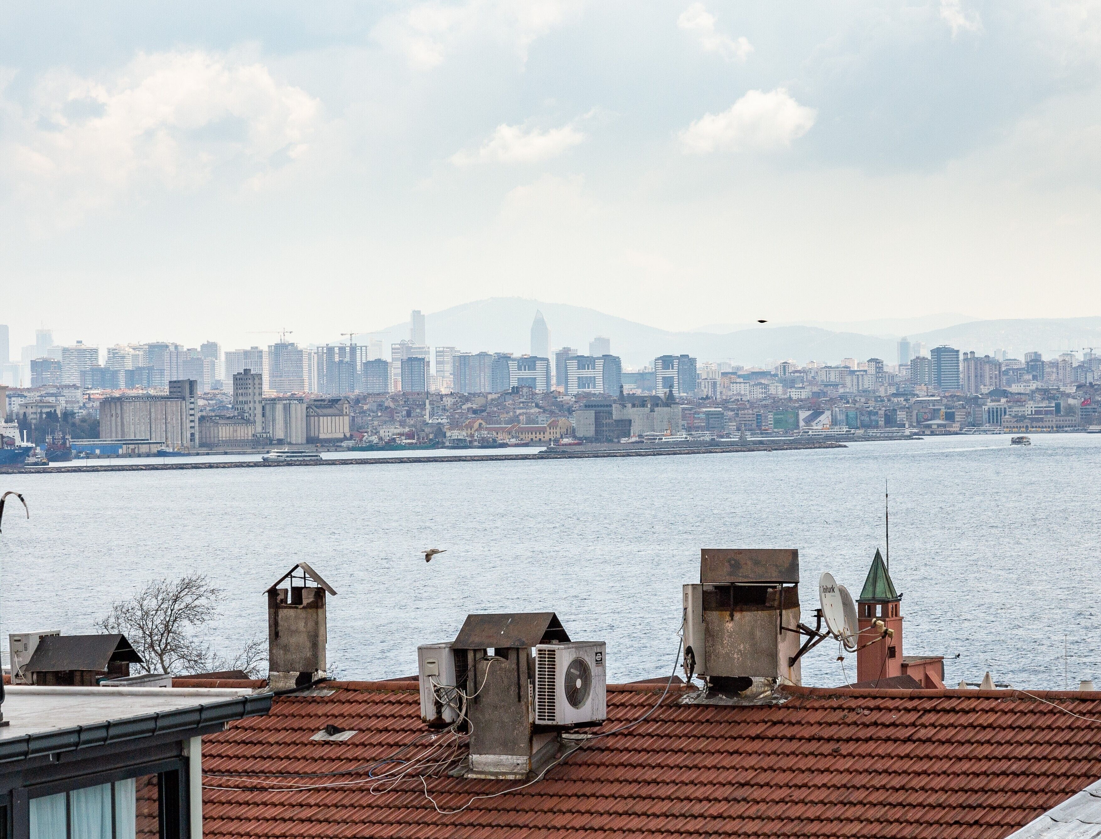 A cityscape with a river in the foreground and a dense urban skyline in the background.