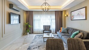 Una sala de estar moderna con un sofá, sillones, una mesa de centro y una araña.