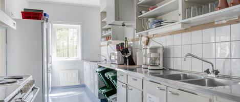 Una cocina moderna con armarios blancos, un lavamanos de acero inoxidable y un ventanal que proporciona luz natural.