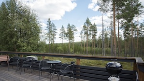 Een houten terras met buitenmeubels en een barbecue.