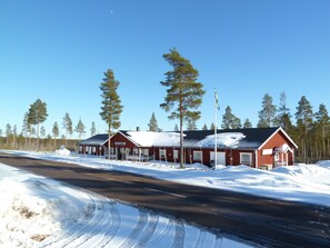 Um edifício vermelho com uma placa que diz "Ski Hotel" em uma paisagem nevada com árvores.