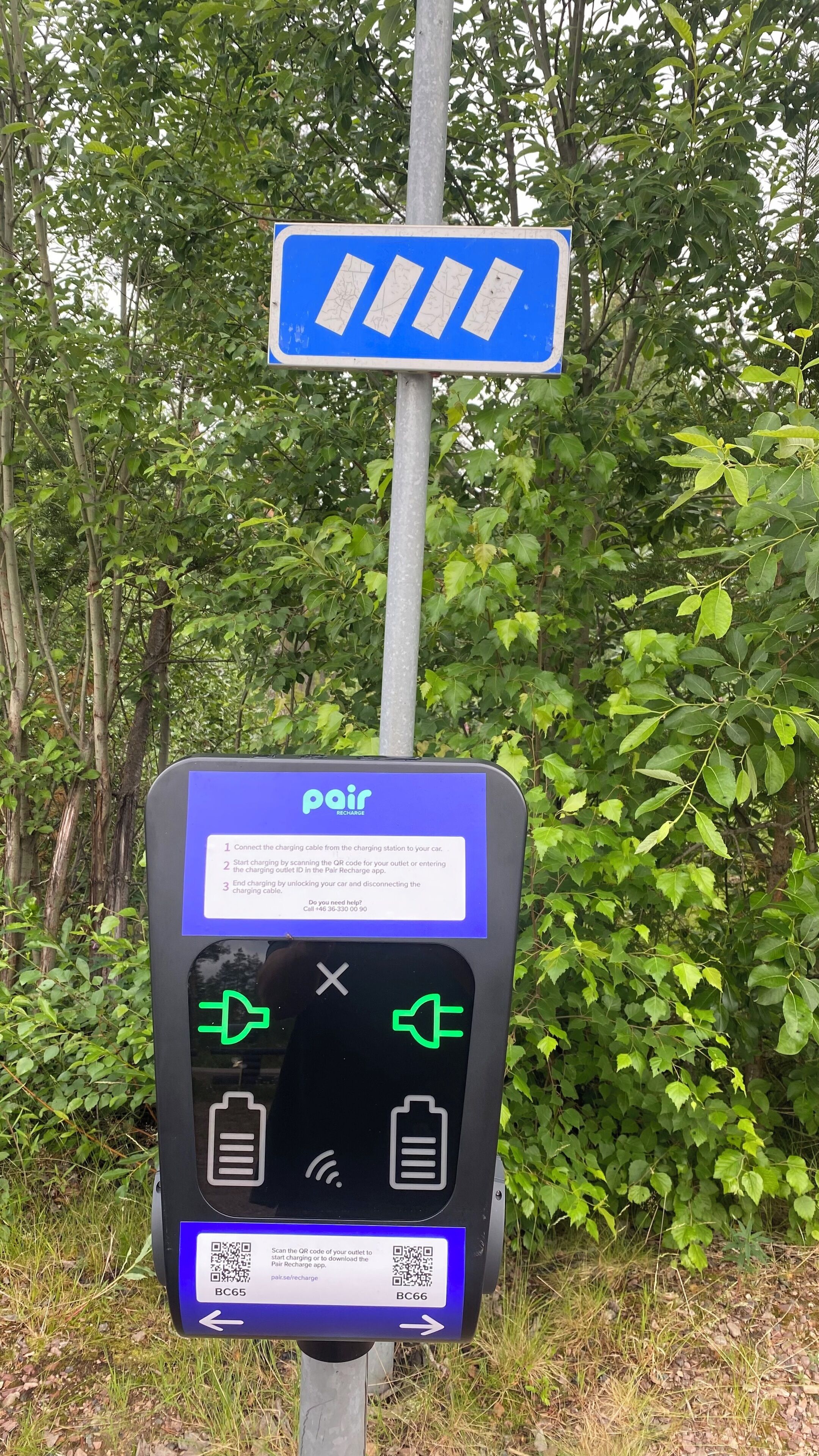 A charging station with instructions and QR codes for a car charging service.