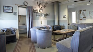Een gezellige woonkamer met een open haard, comfortabele zithoeken en een decoratie van een hertenschedel.
