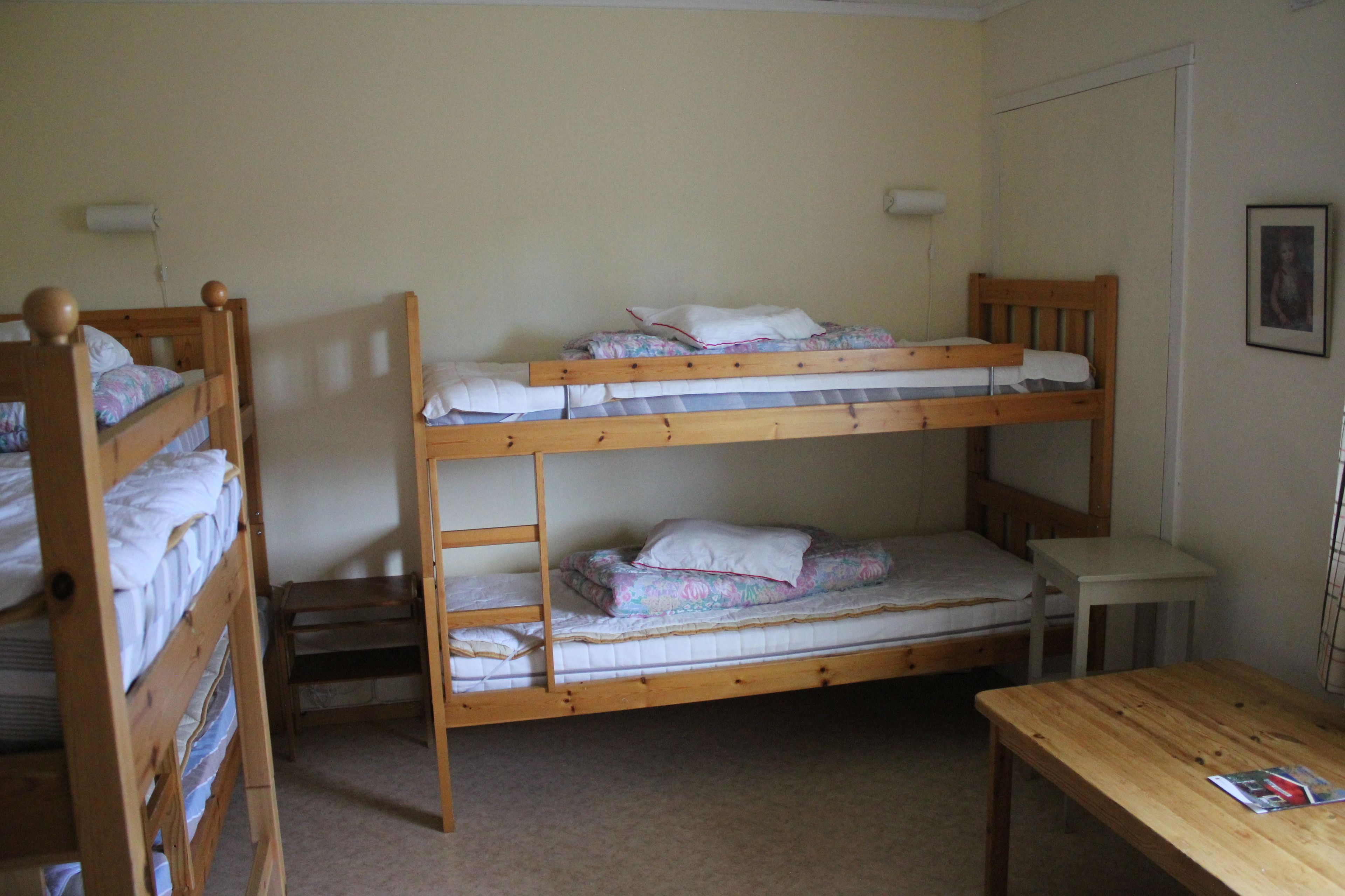 Habitación con literas, una mesita pequeña y un cuadro en la pared.