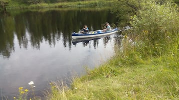 A narrow boat on a calm river surrounded by lush greenery.