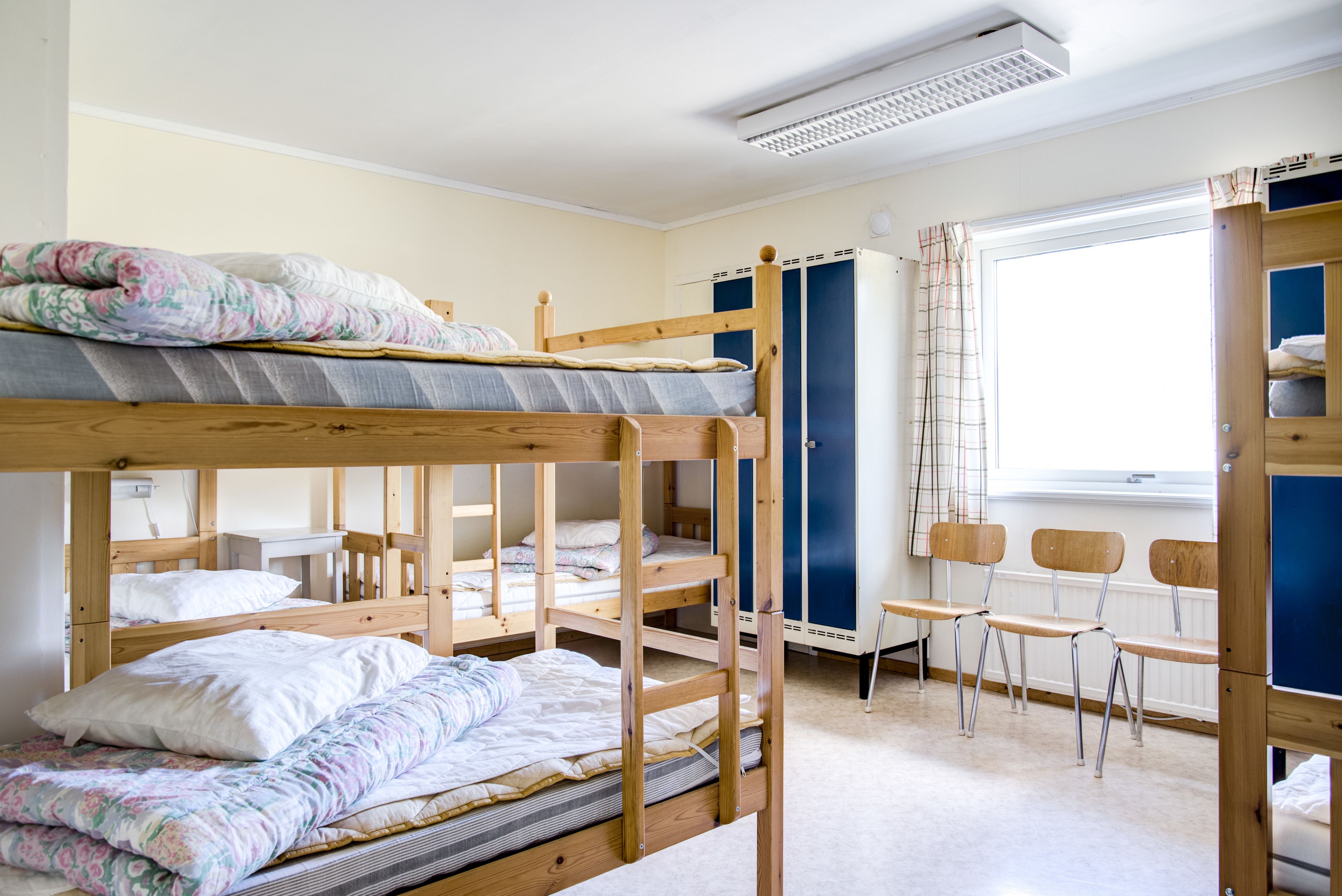 A dormitory room with bunk beds, a desk, and a chair.
