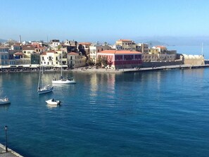 Un pueblo costero con edificios a lo largo de la costa, barcos amarrados y cielo despejado.