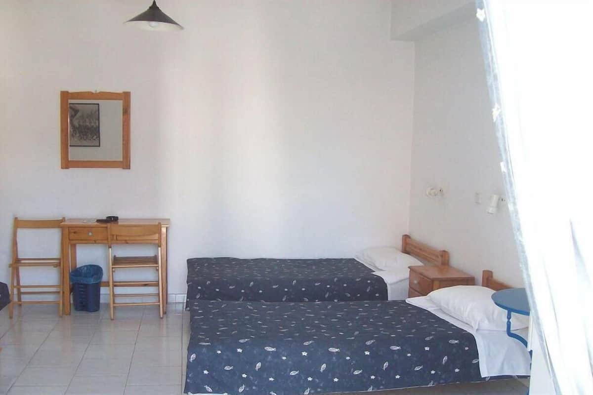 A room with two beds, a desk, and a chair.