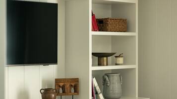 A white cabinet with shelves, a television, and various decorative items.