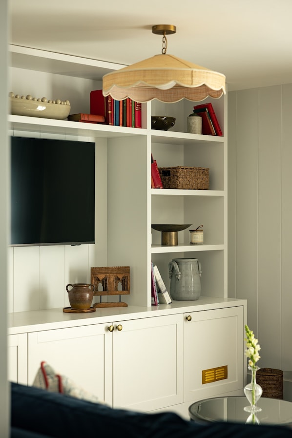 Un mueble blanco con estantes, un televisor y varios objetos decorativos.