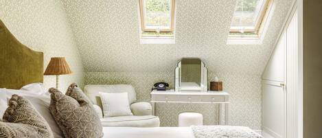 A bedroom with a bed, a nightstand, a desk, and two windows.