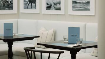 A modern interior with a white sofa, a wooden chair, and a table with a menu.