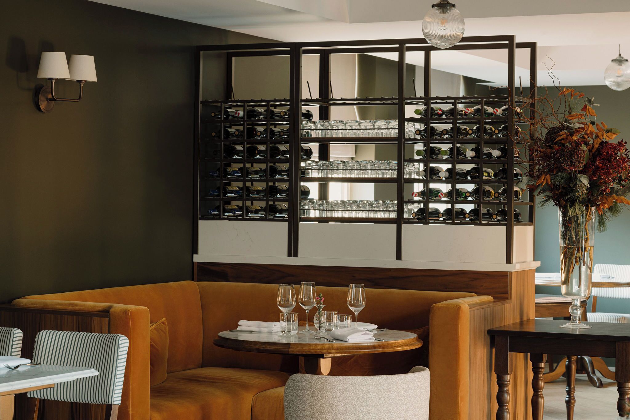 A dining area with a round table set for four, a sofa, and a wall-mounted wine rack.