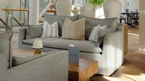 Una sala de estar moderna con un sofá gris, dos lámparas blancas y una mesa de centro de madera.
