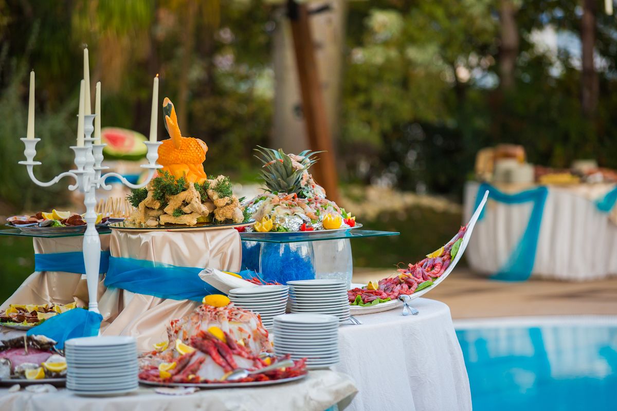 A buffet table with various dishes, a candelabra, and a poolside setting.