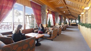 Ein gemütlicher Innenbereich mit Holzwänden und -decken, der mehrere in Reihen angeordnete Sofas und Sessel bietet.