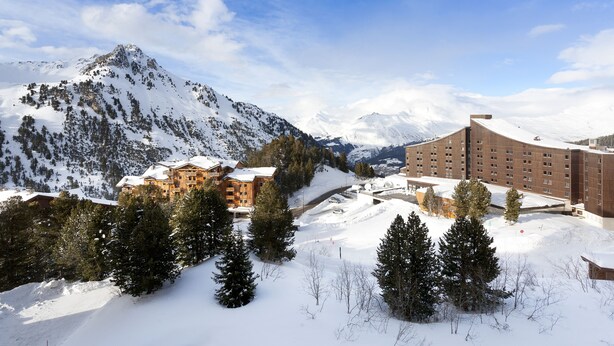 Eine verschneite Berglandschaft mit einem Hotel und einem Skigebiet.