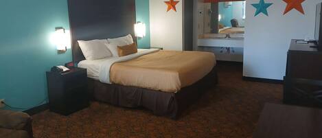 A hotel room with a bed, bedside tables, a desk, and a mirror.
