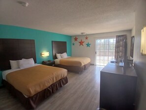 A hotel room with two beds, a desk, a TV, and a balcony with a view. - Howard Johnson by Wyndham Branson Theatre District (Branson)
