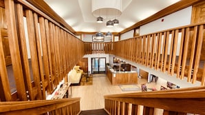 Eine großzügige Hotelhalle mit einer Holztreppe, einer Rezeption und einer Sitzecke.