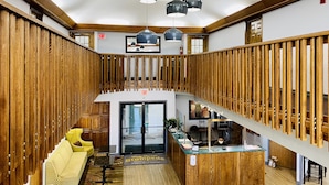 Ein modernes Interieur mit einem Holzbüro, einem gelben Sofa und einer Treppe mit Holzhandläufen.
