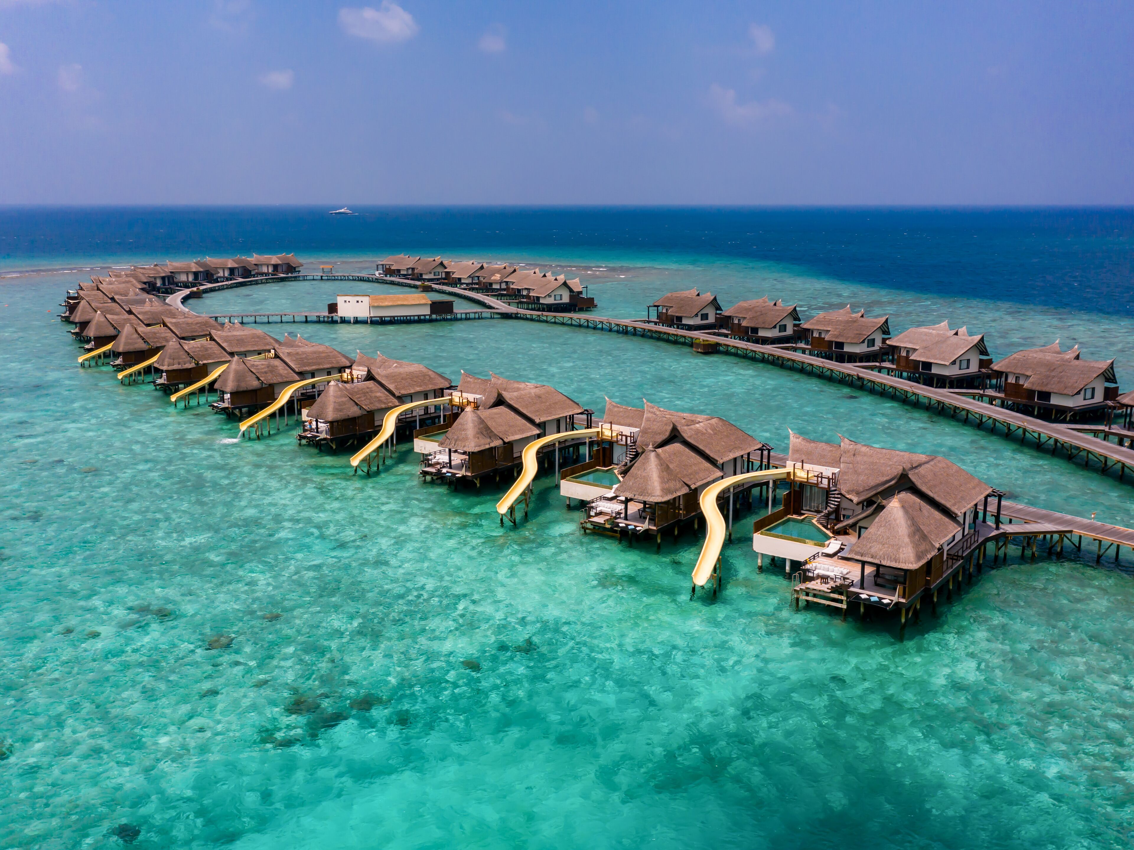 Overwater bungalows connected by walkways over turquoise waters.