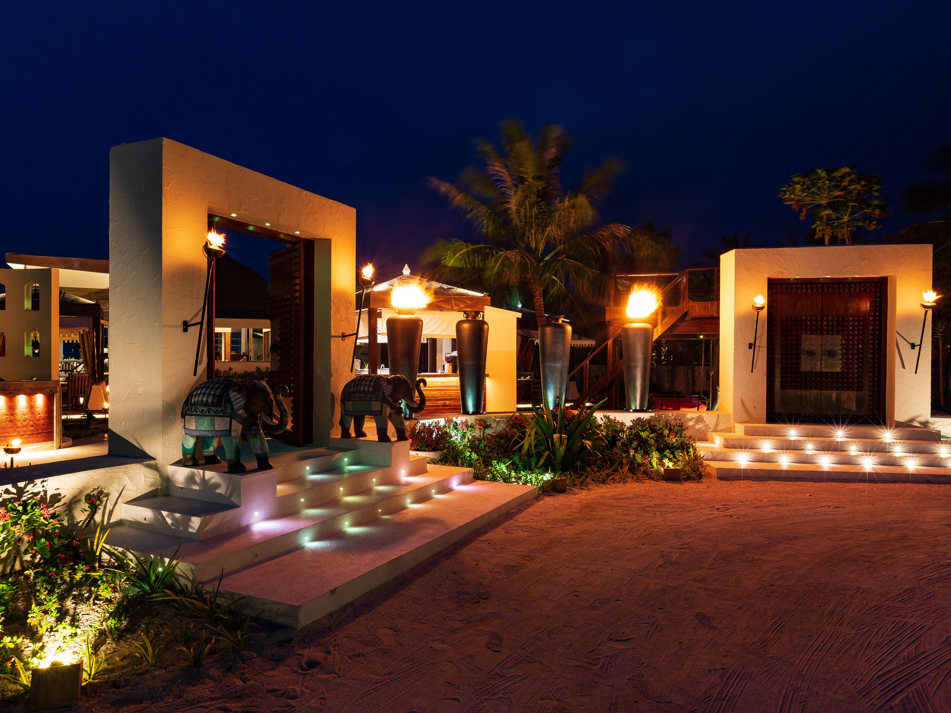 A well-lit outdoor area with a pool, steps leading to a building, and decorative elephant statues.