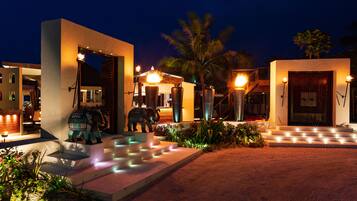 A well-lit outdoor area with a pool, steps leading to a building, and decorative elephant statues.