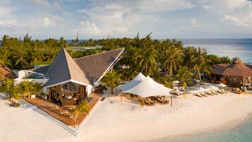 A resort with a large white tent, beach chairs, and a pool area.