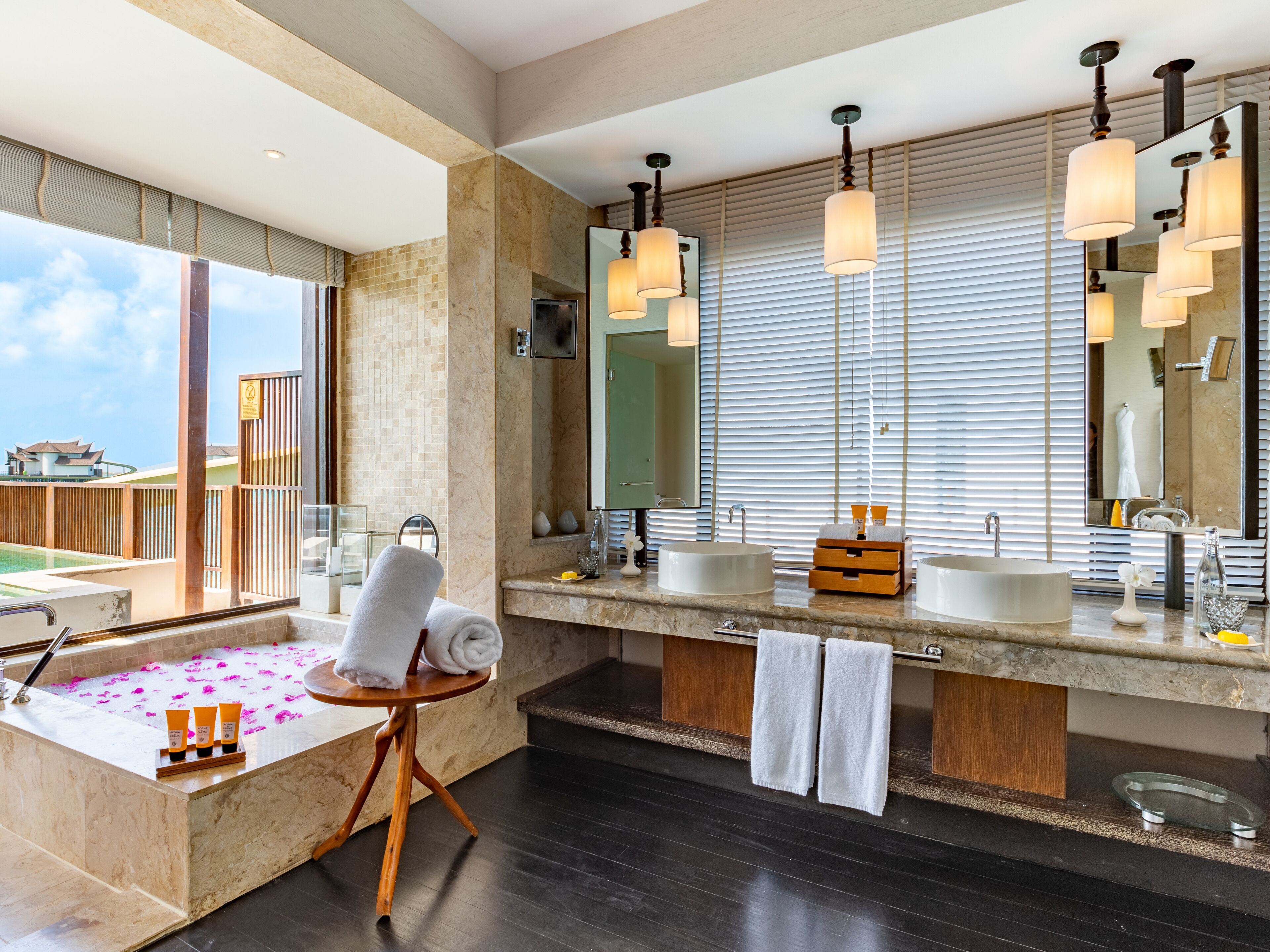 A modern bathroom with a large bathtub, two sinks, and a large mirror.